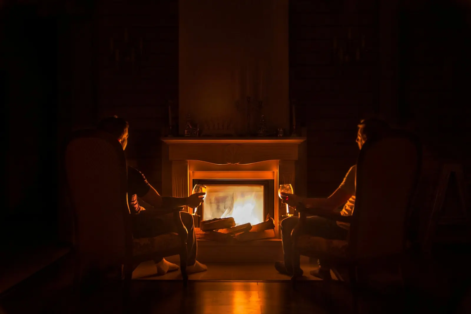 Two people sitting by a wood fire in the evening